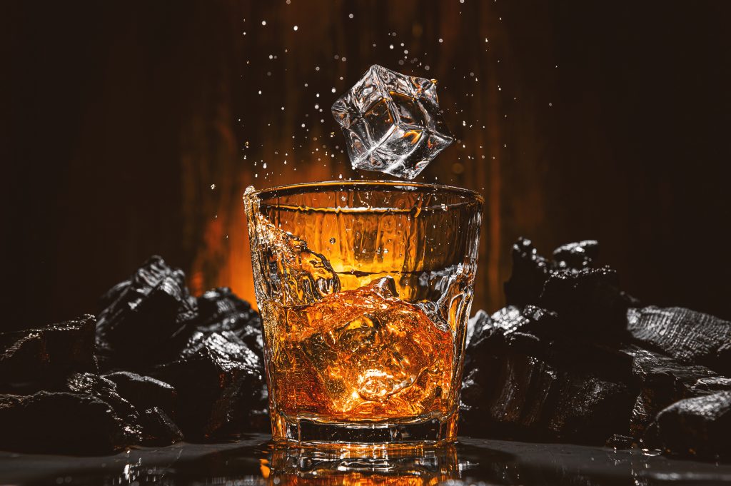 cubitos hielo caen vaso bebida alcoholica marron