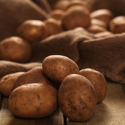 Rustic fresh unpeeled potatoes on a wooden desks